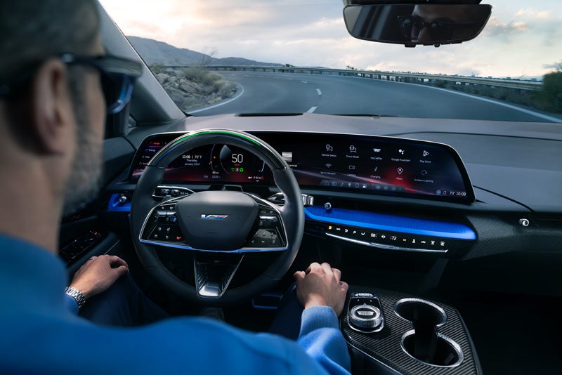 Front View of the 2026 OPTIQ-V Driving Through the Dusk Utilizing its Headlights | Hansen Motor Co Cadillac in Brigham City UT