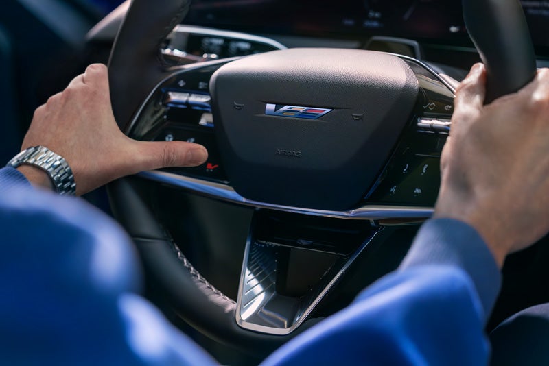 Close-up of a Man About to Press the V-Button on the 2026 OPTIQ-V Steering Wheel | Hansen Motor Co Cadillac in Brigham City UT