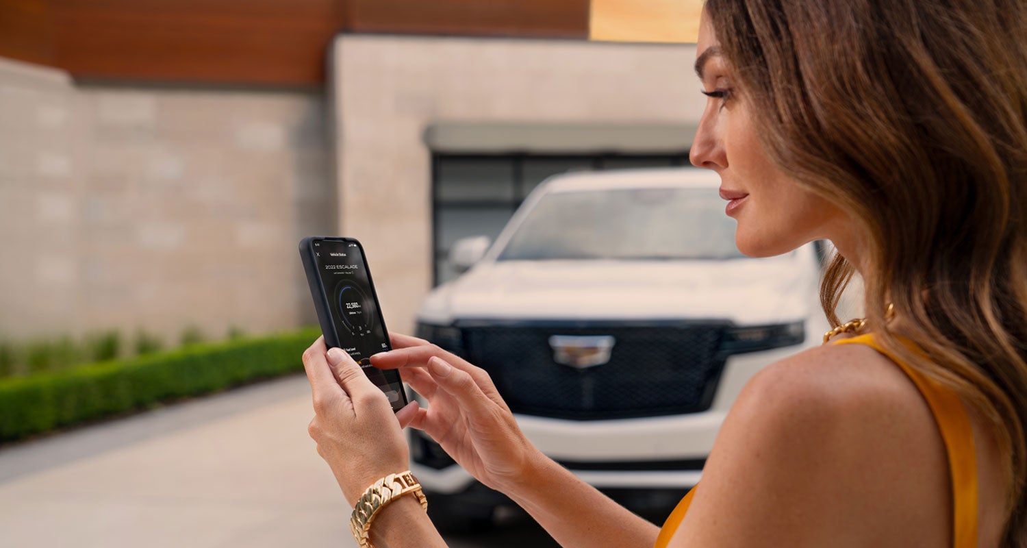 lady checking her mobile with a Cadillac vehicle background | Hansen Motor Co Cadillac in Brigham City UT